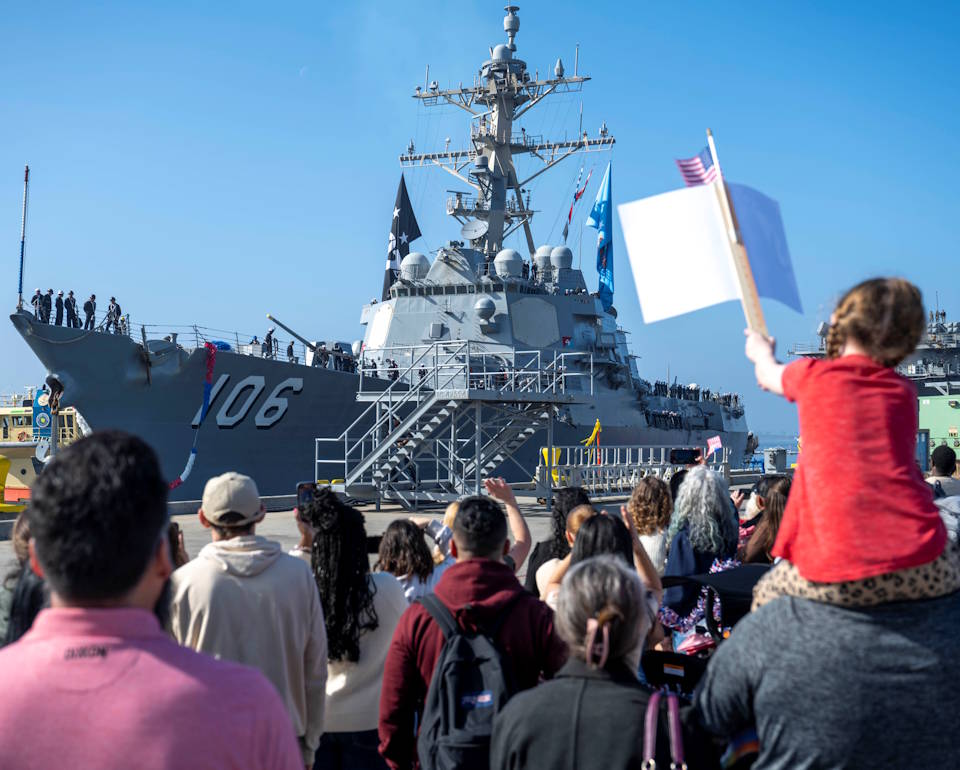 February 21, 2025 - Loved ones of the Arleigh Burke-class guided-missile destroyer USS Stockdale (DDG 106) crew happily wait to greet them as they watch their return at the ship's homeport of Naval Base San Diego from a seven-month deployment. (Image created by USA Patriotism! from U.S. Navy photo by MC Jordan Steis.)