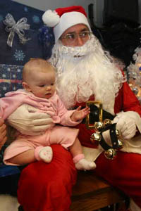 Colonel Marshall I. Considine, commanding officer, Marine Corps Communication-Electronics School, plays Santa for the evening as 5-month-old Brooklynn Lorenzo-Higgins has her photo taken with him at the MCCES staff holiday party Dec. 3 at the Community Center. Photo by: Lance Cpl. Brian A. Tuthill