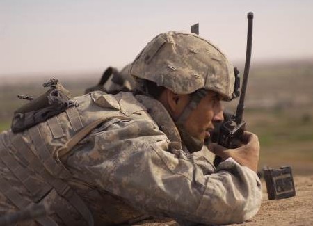 U.S. Army Staff Sgt. Bill Hatzman with Charlie Company, 4th Battalion, 14th Cavalry calls in information on the movement of local Iraqis as he provides an over watch for Army soldiers and Marines looking for weapons caches east of the Syrian border near the Euphrates River on Oct. 4, 2005.